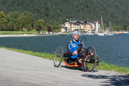 Ein Mann radelt mit seinem Handbike die barrierefreie Route entlang des Achenseeufers in Pertisau.