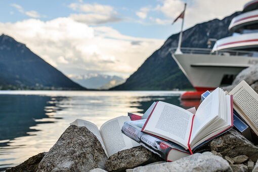 Books worth reading from the achensee.literatour 2018. They were staged on the shore with a view of the lake and the Achensee shipping.