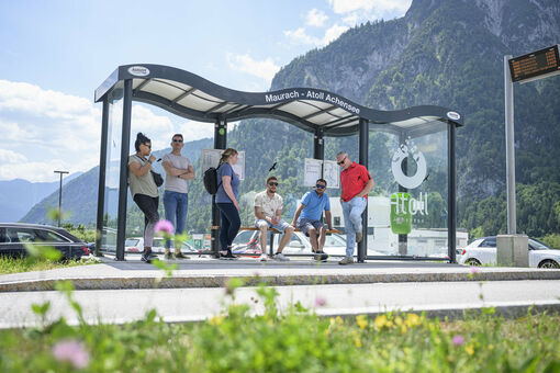 Eine Gruppe Männer und Frauen warten auf den nächsten Bus bei der Haltestelle des Atoll Achensee.