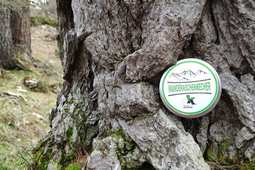 Der Wanderaschenbecher, bestehend aus leeren Munitionsdosen, wird bei einem Baum in Szene gesetzt.